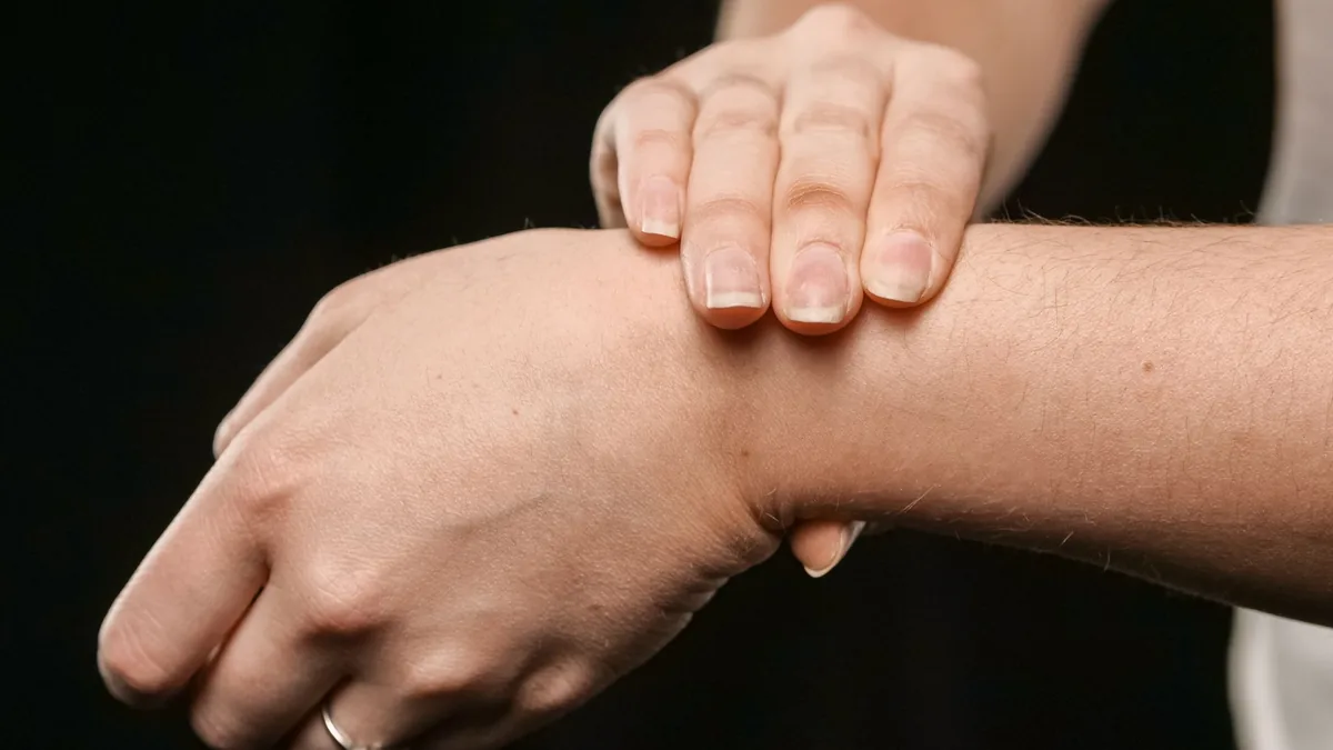One hand pressing on the inside of the other wrist, over the carpal tunnel.